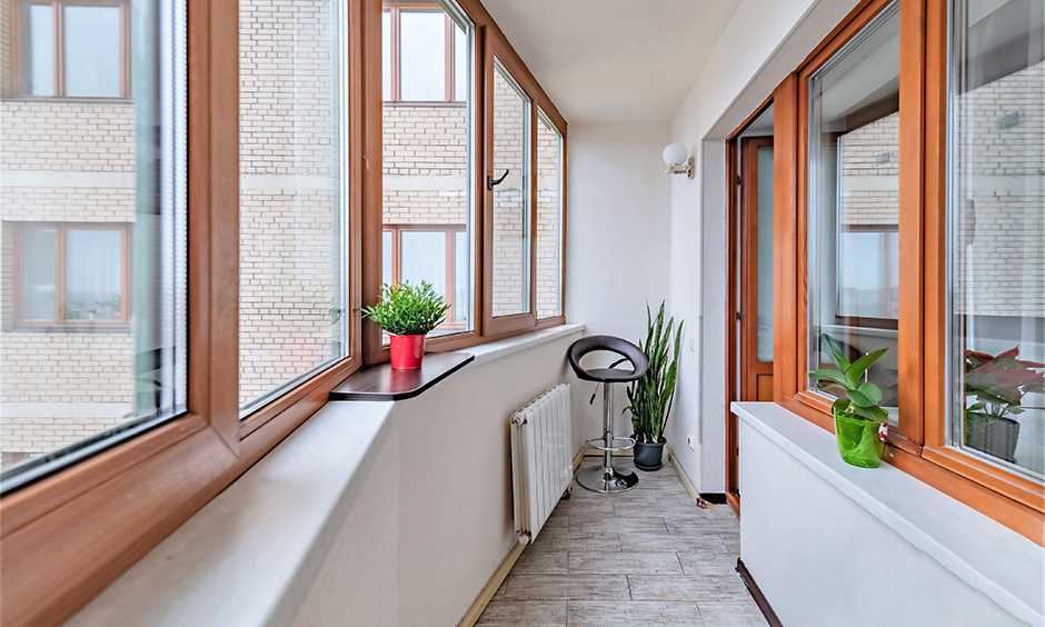 Glass window design for balcony with wooden frames gives the space a hot and earthy look