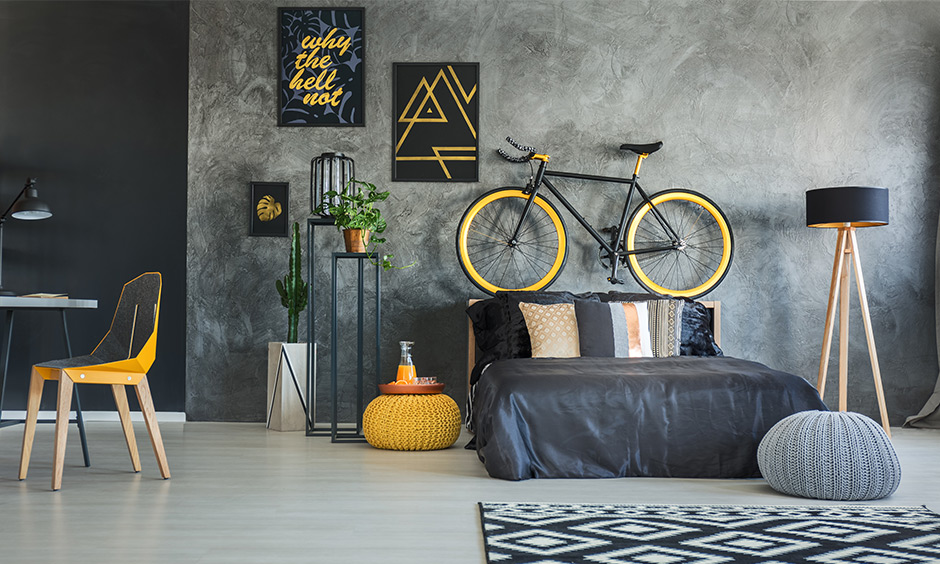 Industrial bedroom design that has yellow picture frames, a pouffe and a wall-mounted cycle