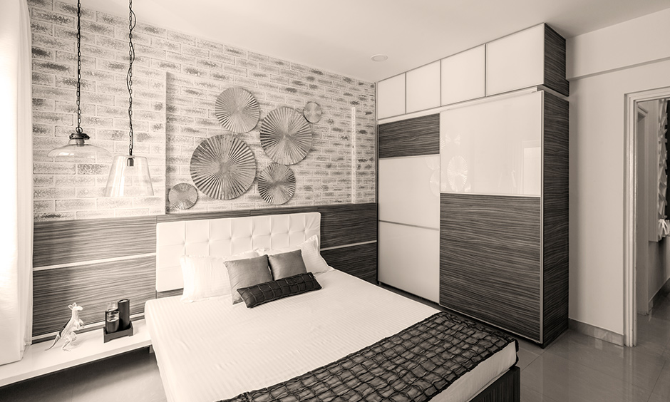 An industrial chic bedroom decorated with weathered brick wallpaper, glass pendant light, and panelled back wall