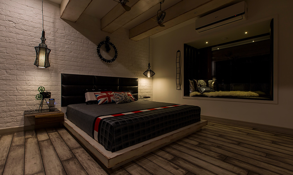 An industrial bedroom design that has soft lighting, warm colour tones in the paint, and soft furnishing