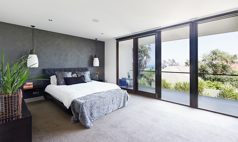 Master bedroom with balcony designed in minimalistic with glass railing is the best bedroom with balcony design