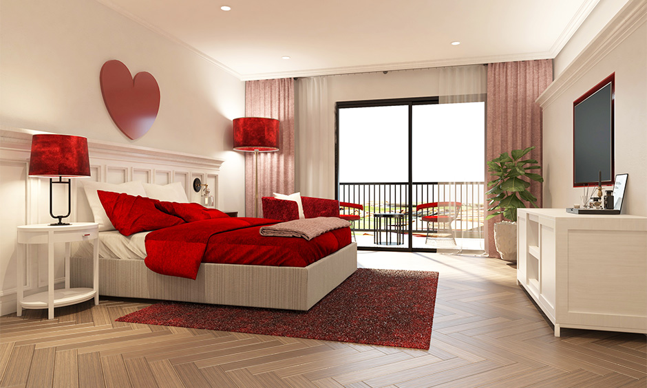 A beautiful red bedroom with balcony furnished with red metallic patio chairs and a coffee table is ideal for couples