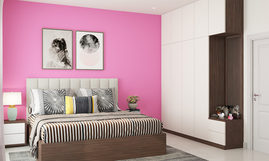 A pink girl bedroom designed with a pink accent wall balances the room’s white and brown palette