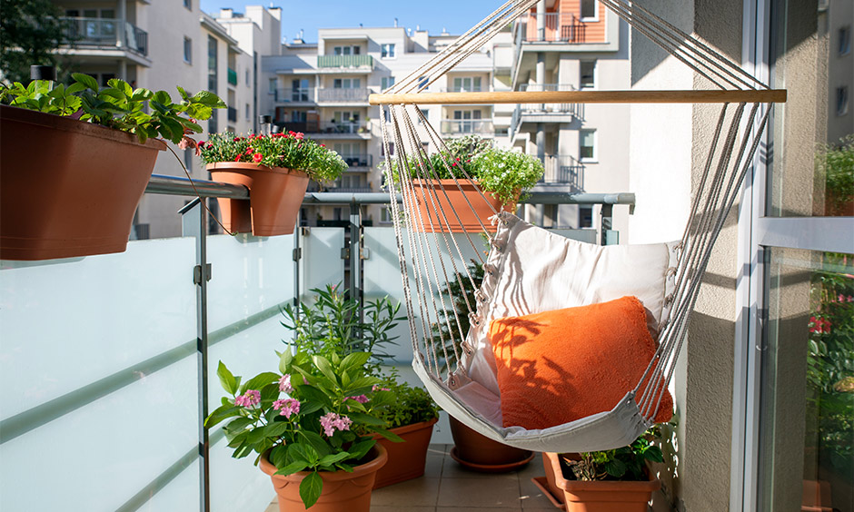 Small apartment balcony decor with a swing and flowering plants makes the outdoor space more inviting