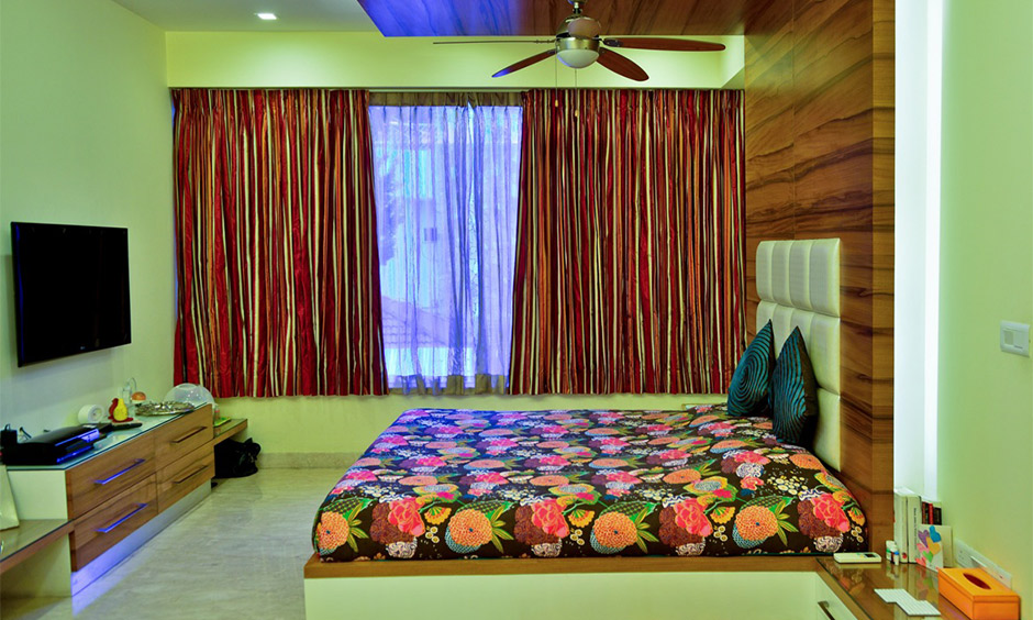 A modern wooden false ceiling design for a den-like bedroom with an extended headboard