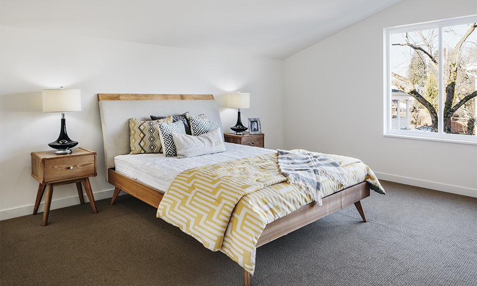 A simple mid-century modern bedroom in the attic with an angled headboard defines mid-century