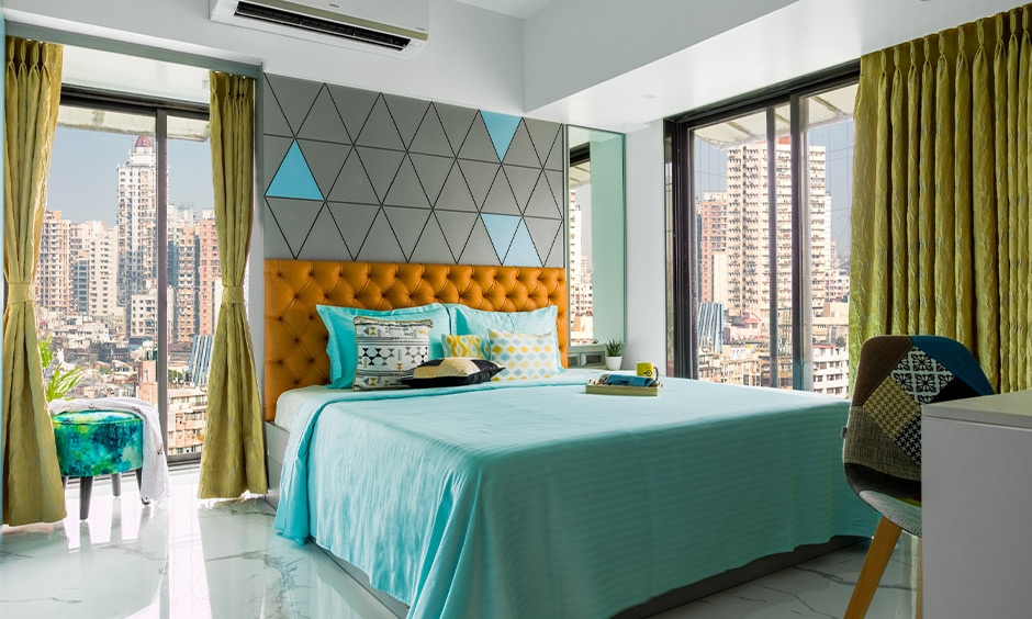 A white and blue master bedroom with geometric accent wall by best budget interior designers in mumbai