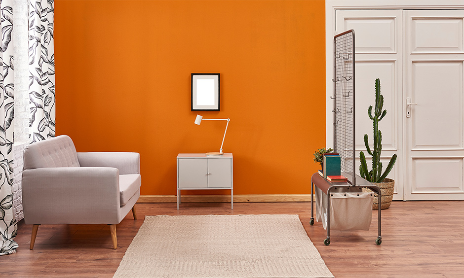 A white floral curtain for the orange wall gives the space a royal and spacious look