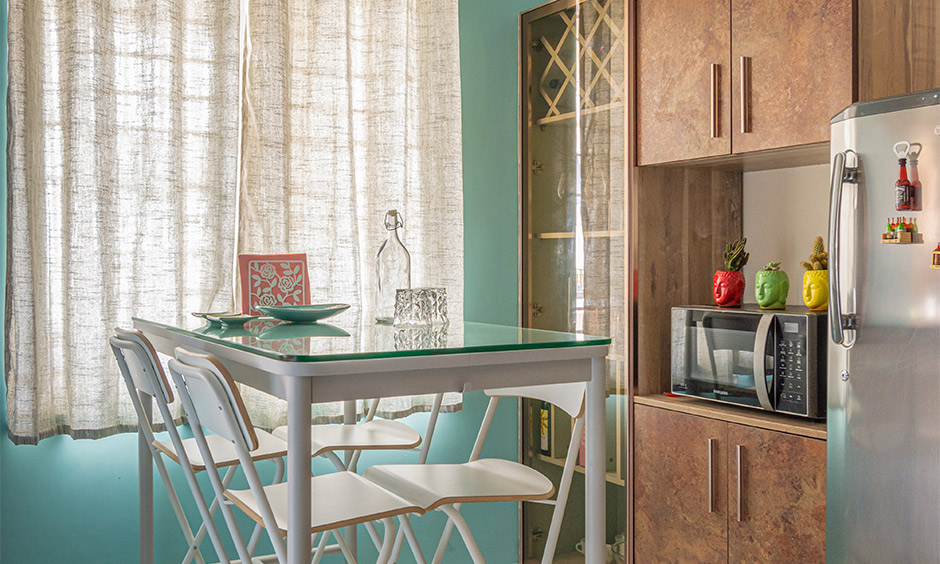 Interior designers in Osman Nagar, Hyderabad, designed this 3BHK dining room with a glass-top dining table and crockery unit