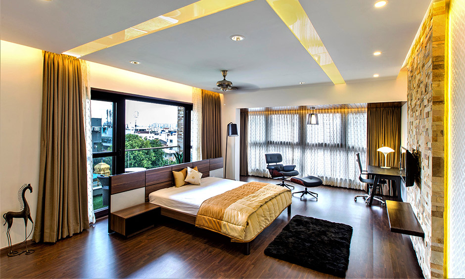 An eclectic master bedroom with a brick-textured accent wall and ceiling panel lights creates an element of excitement