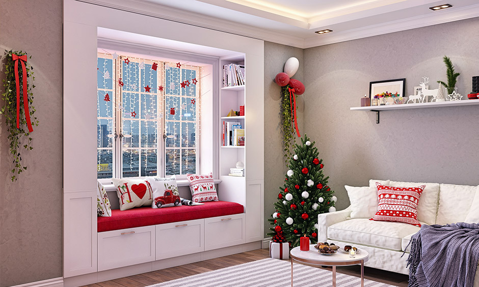 Red and white Christmas tree decor in living room corner blends with Christmas-themed lights on the window